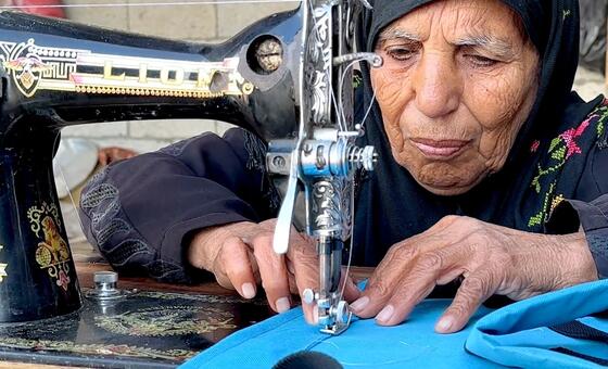 تجلس السيدة المسنة، نغين بن عيسى، خلف ماكينة خياطة بالية، وهي تحرك يديها بعناية أثناء إصلاح الملابس لعملائها. هذا العمل ليس خيارًا بل ضرورة فرضتها الحرب بعد انقطاع المساعدة الاجتماعية التي كانت أسرتها تعتمد عليها.